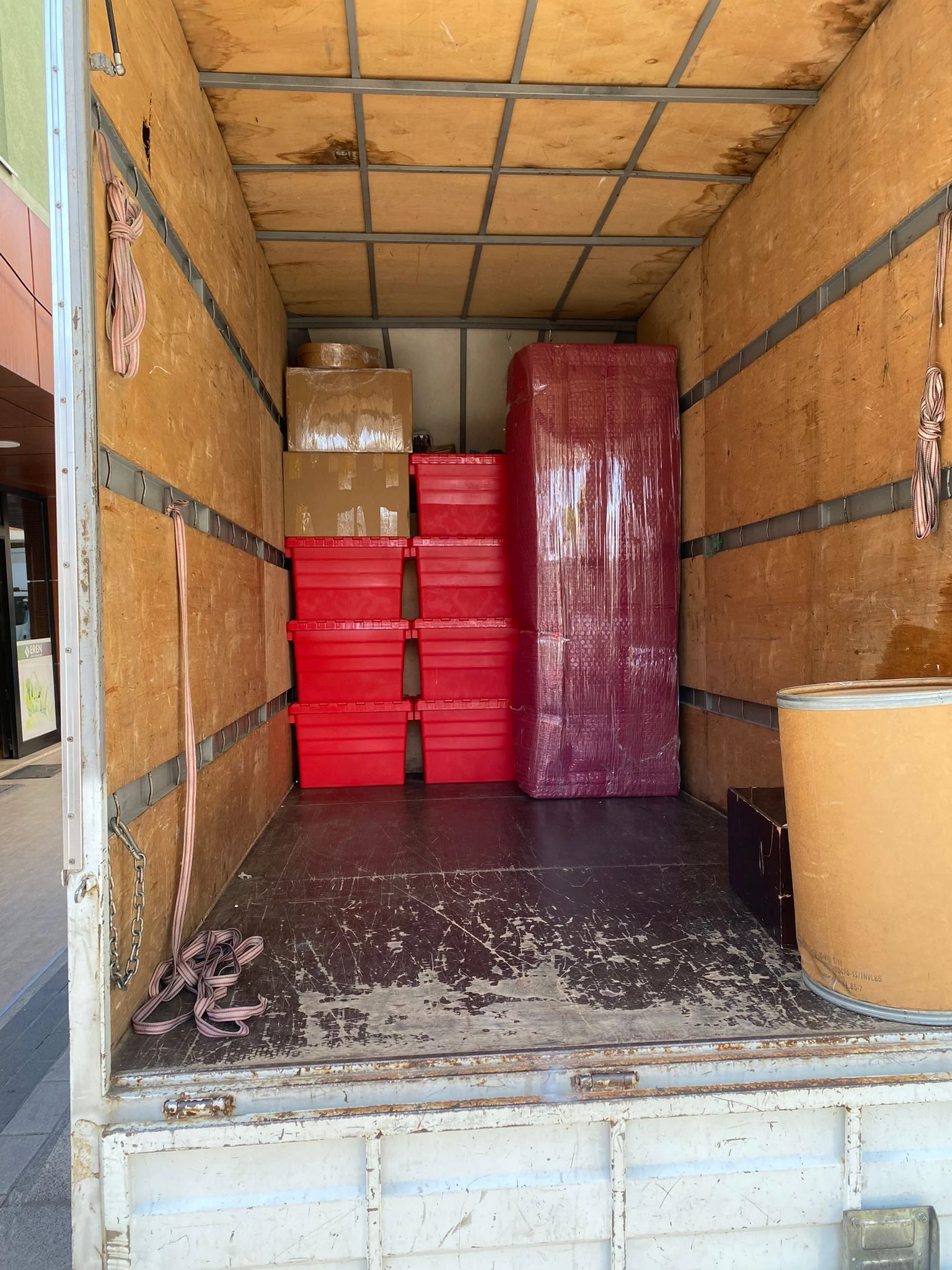 A woman in a mustard-colored sweater packing a cardboard box.